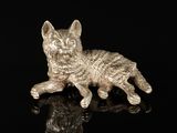 une figurine en argent représentant un chat, posée sur un fond noir