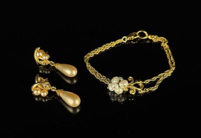 a gold bracelet and earring set with pearls on a black background