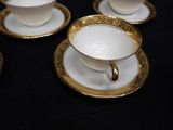 four cups and saucers sitting on a black table