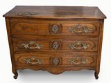 une vieille commode en bois dont les tiroirs sont ornés de ferrures en laiton