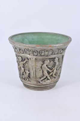 un vase argenté avec un socle vert sur fond blanc