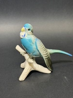 a figurine of a blue parakeet sitting on a branch