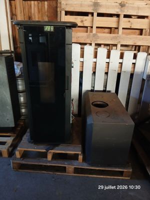 a black refrigerator sitting on a pallet next to other appliances