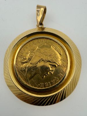a close up of a coin in a gold pendant on a white surface