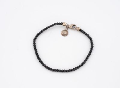 un bracelet en perles noires orné d'un pendentif en forme de crâne