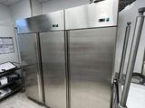 des réfrigérateurs en acier inoxydable dans une cuisine professionnelle, à côté d'une étagère métallique