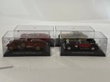two model cars in a display case on a white surface