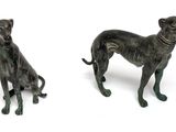 two bronze figurines of two dogs on a white background