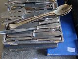 a lot of silverware on a blue cloth