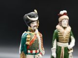 two figurines of men dressed in military clothing and hats