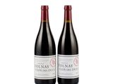 two bottles of red wine sitting next to each other on a white surface