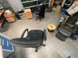 une chaise de bureau noire posée dans une pièce encombrée