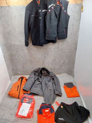une pièce où se trouvent un lit, une veste et d'autres objets par terre