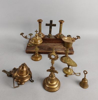 several antique brass bells and a cross on a wooden stand