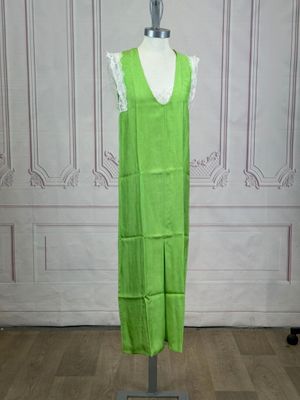 green dress on a mannequin stand in front of a white wall