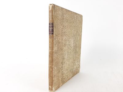 an old book sitting on top of a white table next to a white wall