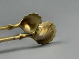 une cuillère en or et son repose-cuillère posés sur une surface grise
