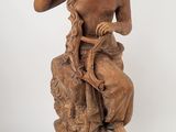 statue représentant une femme assise sur un rocher, tenant un oiseau dans la main