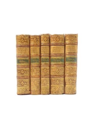 quatre vieux livres posés l'un sur l'autre sur une surface blanche