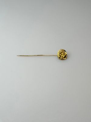 a close up of a gold pin with a flower on it