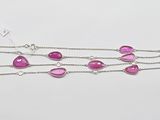 a close up of a necklace with pink stones on a white background