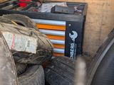 a pile of old tires in a garage with tools on the wall