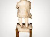 statue of a child sitting on a stool on a white background