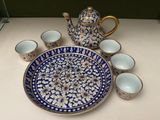 a blue and white plate with cups and a teapot on it