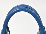blue leather handbag with gold zippers on a white background