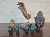 une statue représentant une personne tenant une main au-dessus d'un ensemble de vases posés sur une table