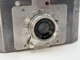 a silver camera with a black lens on a white surface