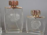 three glass perfume bottles with a gold top and a flower in the middle