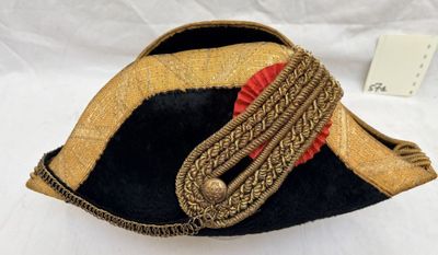 un chapeau noir et doré orné d'un ruban rouge