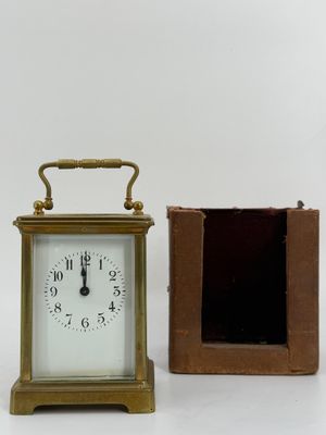 a small clock sitting next to a box on a table