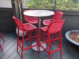four red chairs and a table on the deck