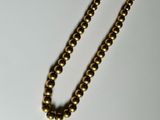 a gold necklace with a gold ball on a white surface