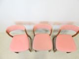 three pink chairs sitting on top of a white floor next to a wall