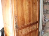 a wooden cabinet with a glass door in the corner of a room