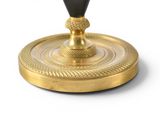 a gold candle holder with a black candle on it