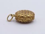 a close up of a gold pendant on a white surface