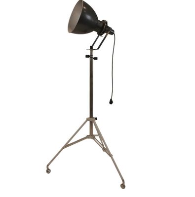 une lampe noire et argentée posée sur un trépied, sur fond blanc