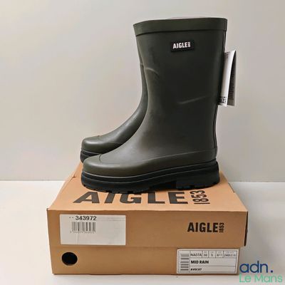 une photo représentant une paire de bottes en caoutchouc noires posées sur une boîte