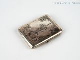 a silver cigarette case with a picture of a man riding a horse