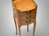 a small wooden table with three drawers on top of it