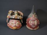 two wooden masks with faces on them sitting next to each other