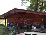 an image of a red shed with a lot of junk on the ground