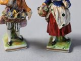 two figurines of a woman and a man holding baskets