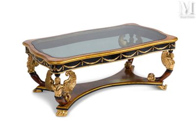 une table basse avec un plateau en verre et des motifs dorés