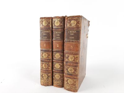 two old books sitting on top of each other on a white surface