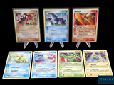 Plusieurs cartes Pokémon sont disposées sur une table avec un fond noir.